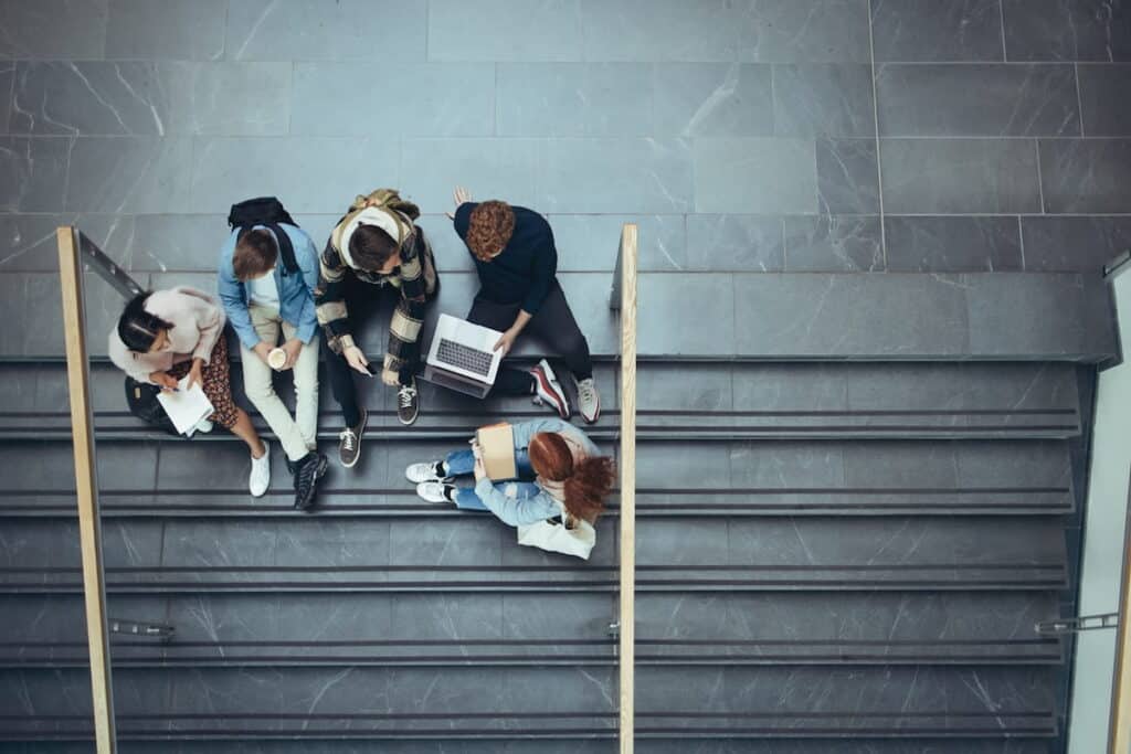 A group of students sit on the stairs of a building.