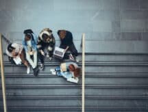 A group of students sit on the stairs of a building.