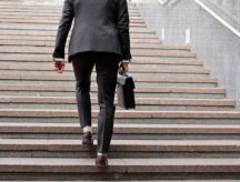 A businessman holding a briefcase climbs up a flight of stairs