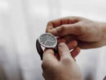 Closeup shot of black and silver watch in a man's hands.