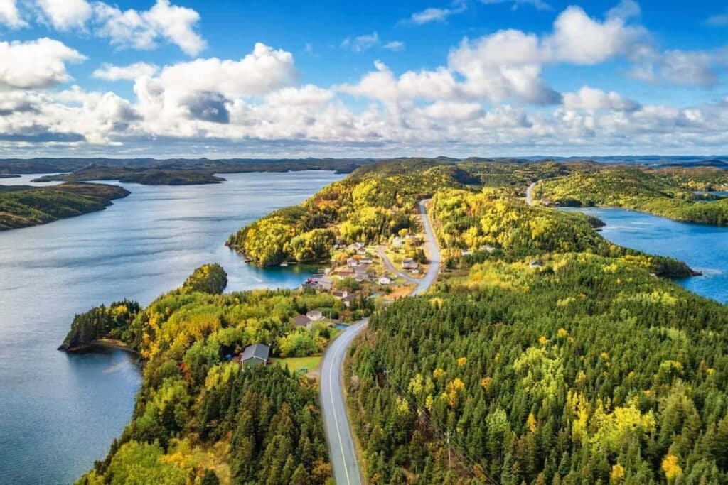 Aerial shot of small town coast in Newfoundland and Labrador on a sunny day, with the ocean visible in the back.