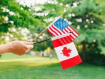Hand holding Canadian and American flag