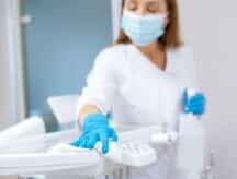 A worker in protective gloves cleaning work surface in a clinic