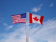 The Canadian and American flags flying beside each other