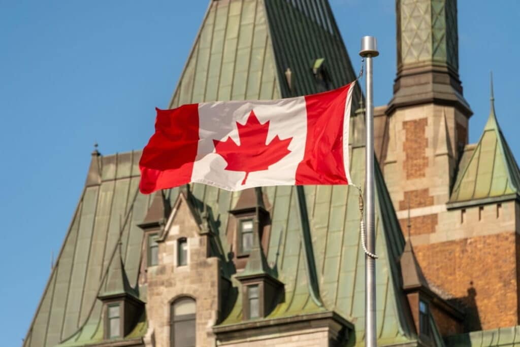 A closeup shot of the Canadian flag against the Canadian Parliament building.
