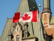 A closeup shot of the Canadian flag against the Canadian Parliament building.