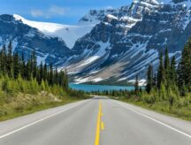 A Spring evening view of Icefields Parkway extending towards Bow Lake, with BowCrow Peak, Crowfoot Glacier and Crowfoot Mountain rising high behind, Banff National Park, AB, Canada.