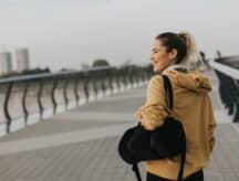 A woman looks out across a bridge on an overcast day.