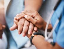 A close up of a healthcare worker comforting a patient.