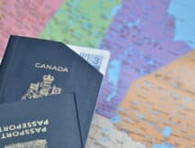 A Canadian passport sits atop a map of Canada, with a boarding pass barely visible within the folds of the document.