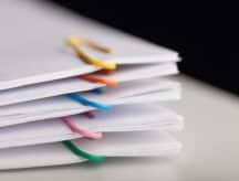 A stack of files with different coloured paper clips adorning each pile.