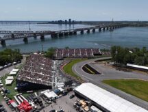 A shot of the Montreal F1 circuit in 2025, with crowded grandstands, water channels, and city skyline, shot from a Helicopter.