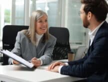 Lawyer with clipboard working with client at table in office