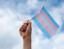 A hand holds a transgender pride flag