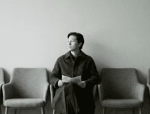 A man waits disappointedly for his citizenship interview in an empty waiting room, surrounded by empty chairs.