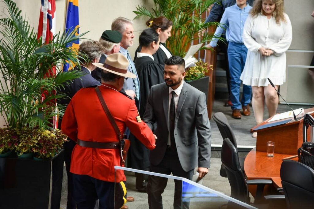 A man shaking hands with an RCMP officer at a Canadian citizenship ceremony in Hamilton, Ontario.