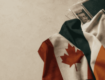A flag of an Irish anf Canadian. flag resting atop a beige background.