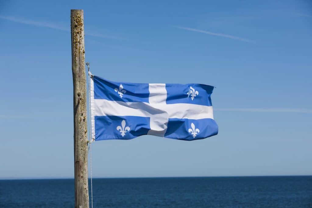 Quebec Provincial flag on wooden pole overlooking Saint Lawrence seaway.