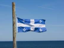 Quebec Provincial flag on wooden pole overlooking Saint Lawrence seaway.