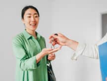 Beautiful asian woman, new property owner, getting keys from realtor after buying house