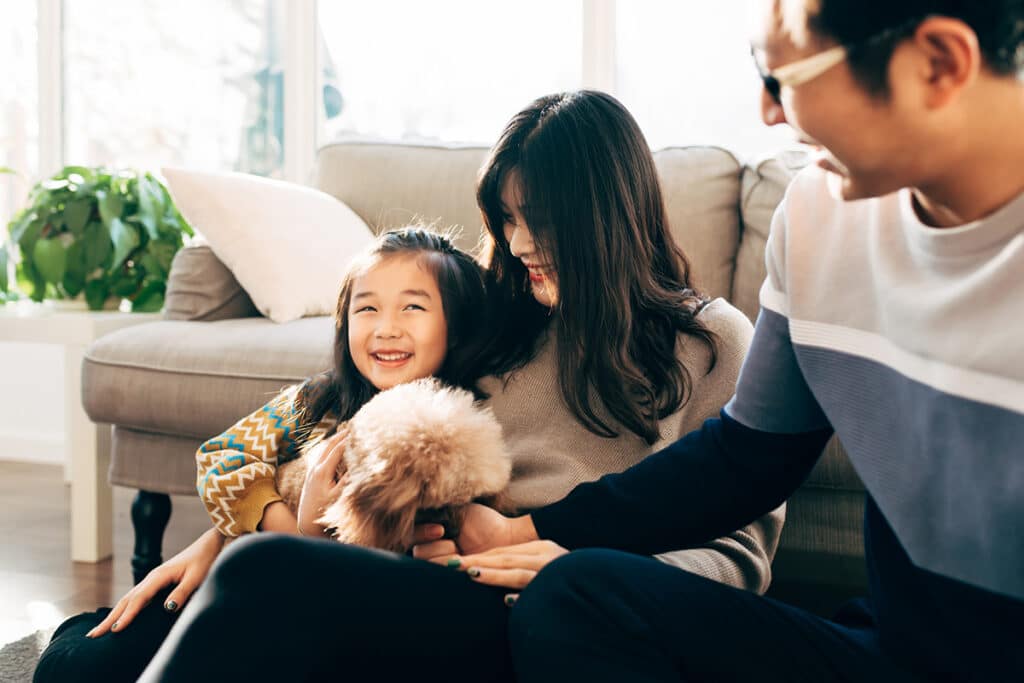 Young Asian family and pet dog playing at home