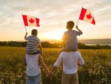 A family of four, with the children waving Canadian flags