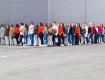 People waiting in a line that goes around a corner.