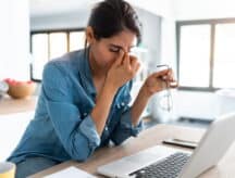 A woman gripping the bridge of her nose in stress.