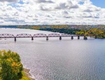 A shot of Fredericton, New Brunswick, Canada, with a bridge and greenery visible.