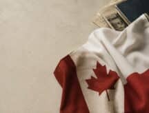 A Canadian and Polish flag sit on a white marble table, with documents in the top right corner.