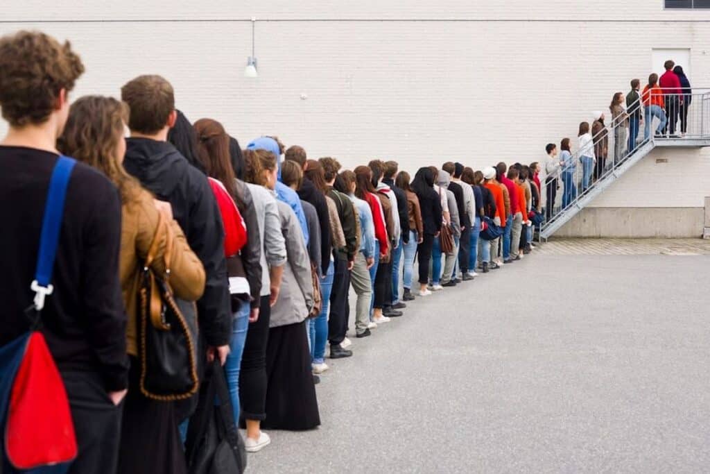 Many people waiting in a long line, to enter a building.