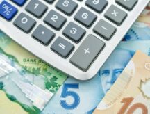 A closeup shot of Canadian dollar bills of varying denominations spread out underneath a calculator.