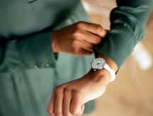 A closeup shot of a woman wearing a green shirt checking her watch.