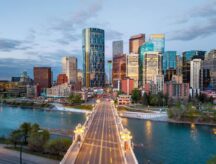 Road bridge leading across Bow River into the downtown Calgary skyline at dawn in Alberta, Canada.