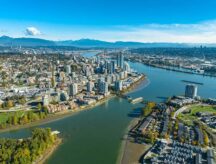 Aerial view of New Westminster, British Columbia, showcasing the city's skyline along the Fraser River on a clear day.