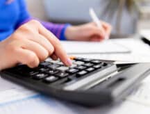 A closeup shot of a woman using a calculator and doing some paperwork.