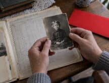 A descendant of a Canadian home child traces their lineage, holding a photo of their ancestor as a child.