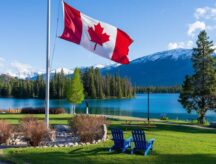 The national flag of Canada with a mountain and forest visible in the back, in Jasper National Park.