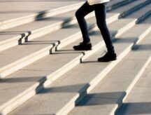 A closeup shot of someone's legs walking up outdoor stairs.