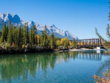 Bow River in Canmore, Alberta, with the Canadian Rockies visible in the back, and the Canmore Engine Bridge in the forefront.