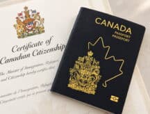 A Canadian passport sits ontop of a Canadian citizenship certificate