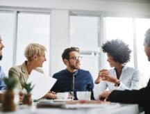Group of workers sitting around a table in an office environment.